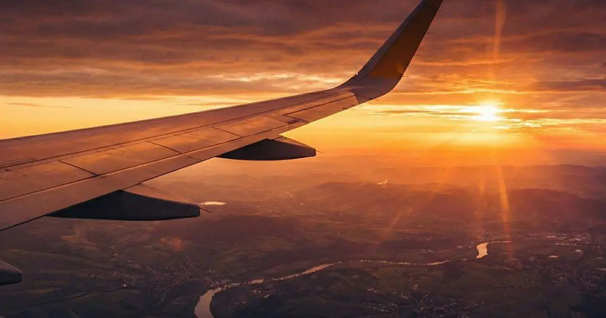 Asa de avião em voo representando o transporte aéreo e o turismo internacional no Brasil.