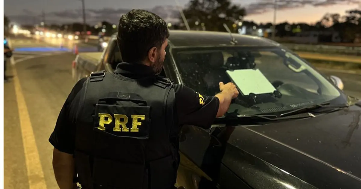 Agente da PRF fiscaliza carro com antena Starlink instalada no para-brisa.