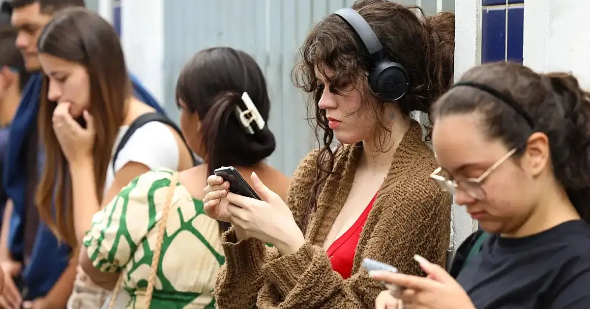 Estudantes utilizando o celular enquanto aguardam informações do Enem.