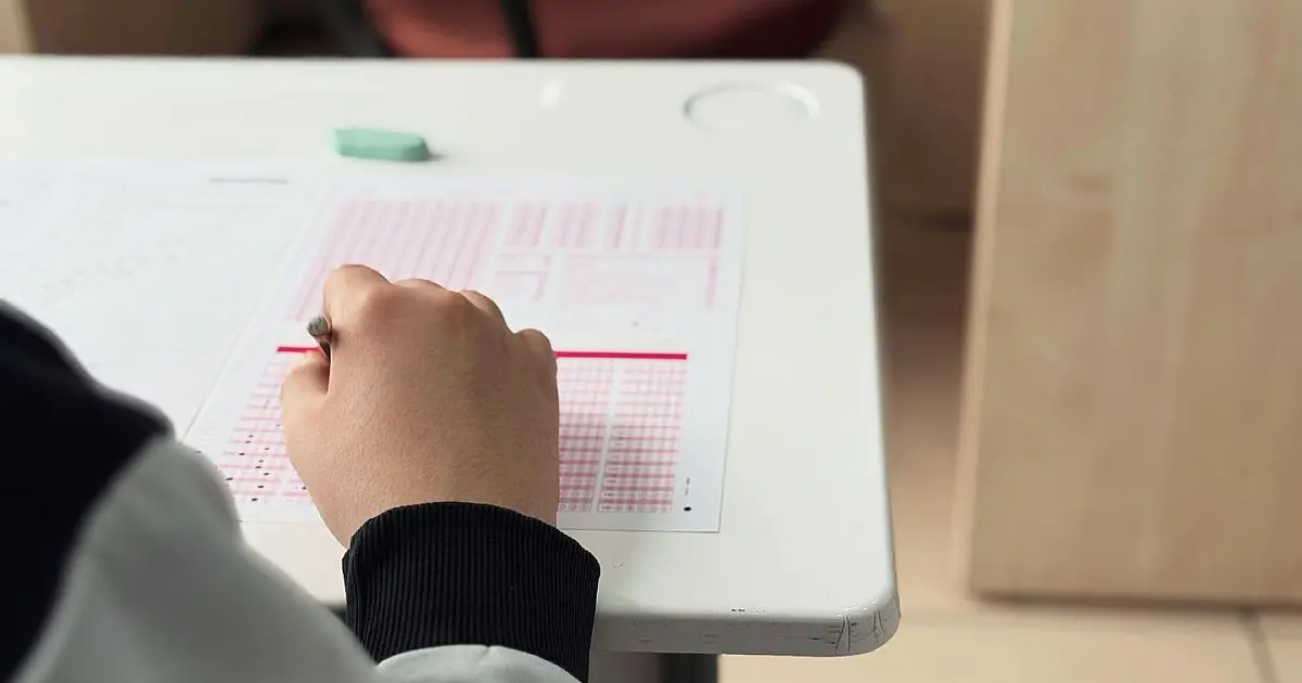 Candidato realizando prova de concurso público em sala de aula.
