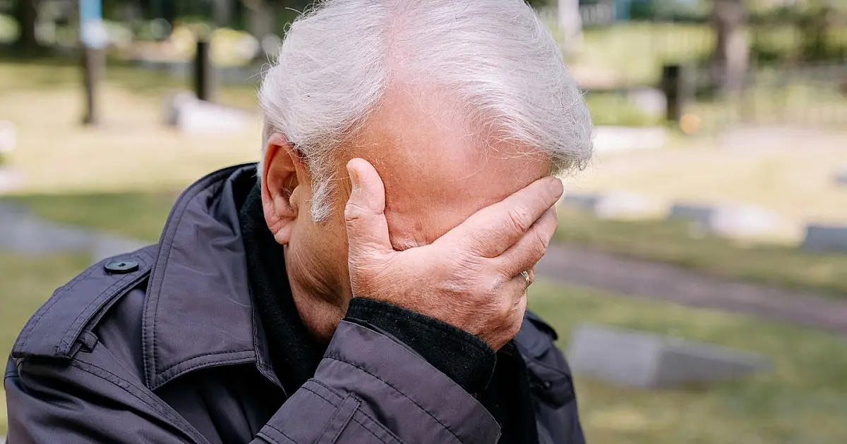 Idoso com a mão no rosto demonstrando frustração após sofrer golpe financeiro