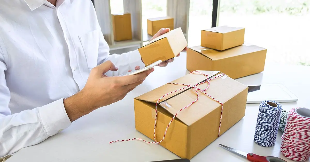 Homem abrindo caixa de encomenda recebida em casa.
