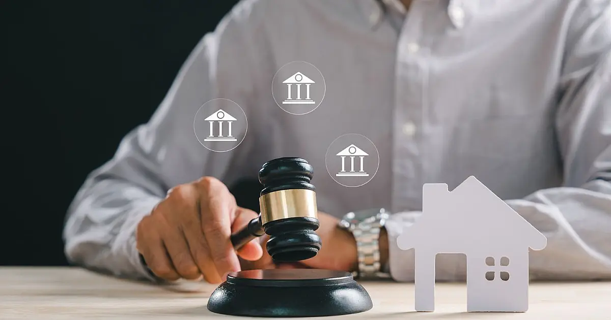 Martelo de leilão ao lado de miniatura de casa representando venda de imóvel