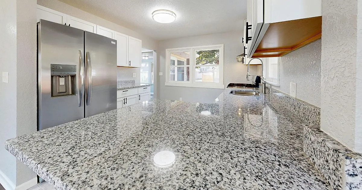 Cozinha moderna com bancada de pedra clara semelhante ao quartzito e design contemporâneo.