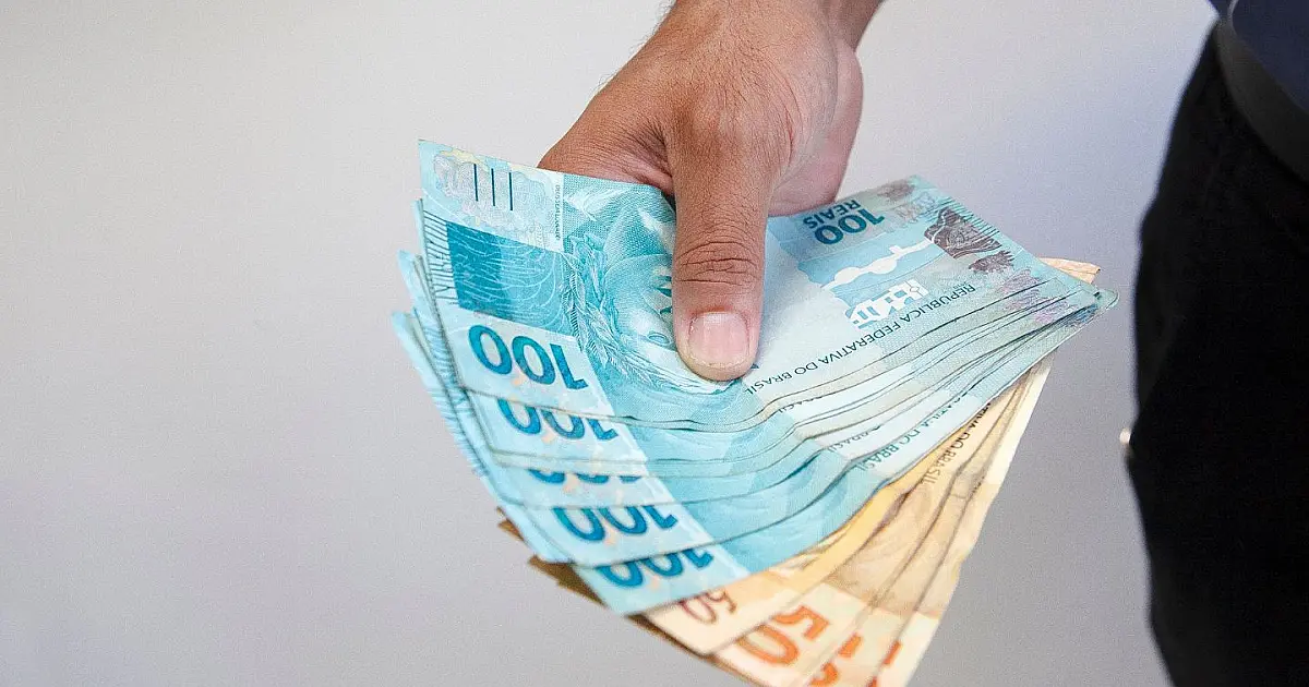Notas de real brasileiro espalhadas sobre mesa representando pagamento de benefício.