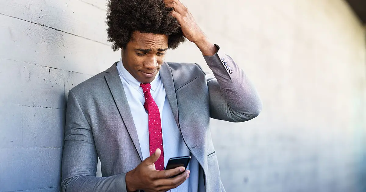 Empresário preocupado utilizando smartphone ao ar livre.