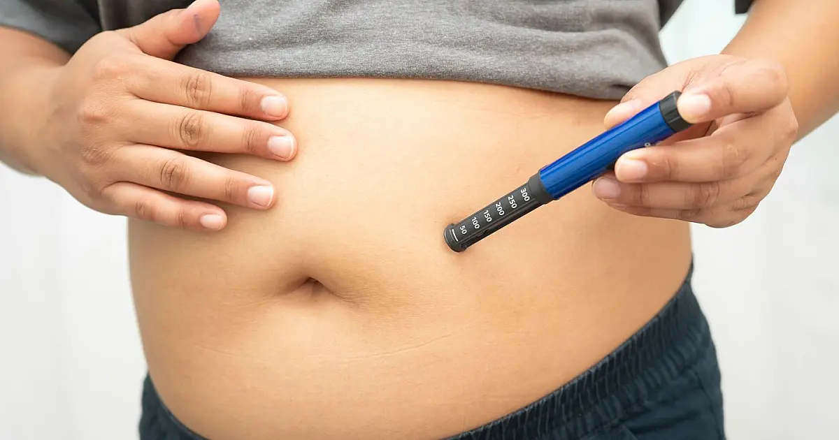 Pessoa aplica caneta emagrecedora no abdômen durante tratamento médico.