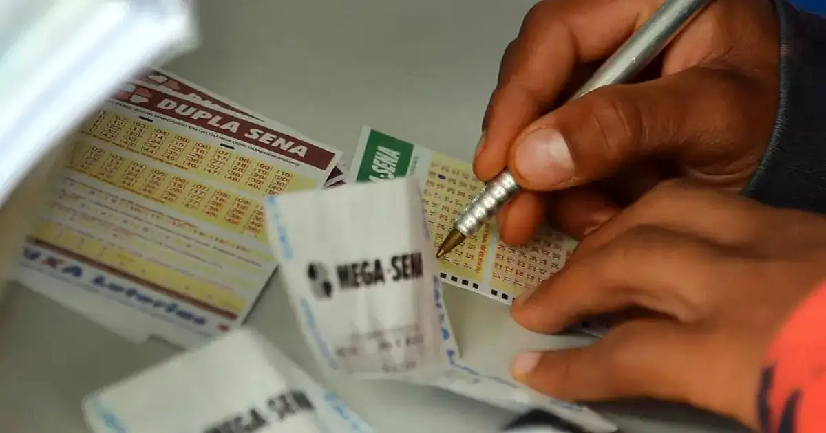 Pessoa preenchendo bilhete da Mega-Sena em uma casa lotérica.