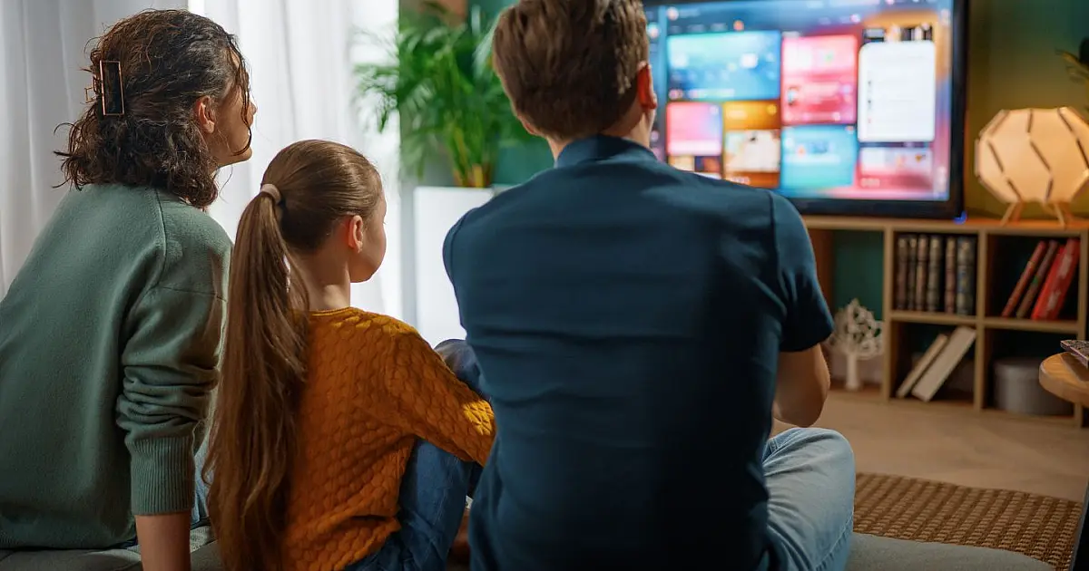 Família reunida na sala assistindo televisão.