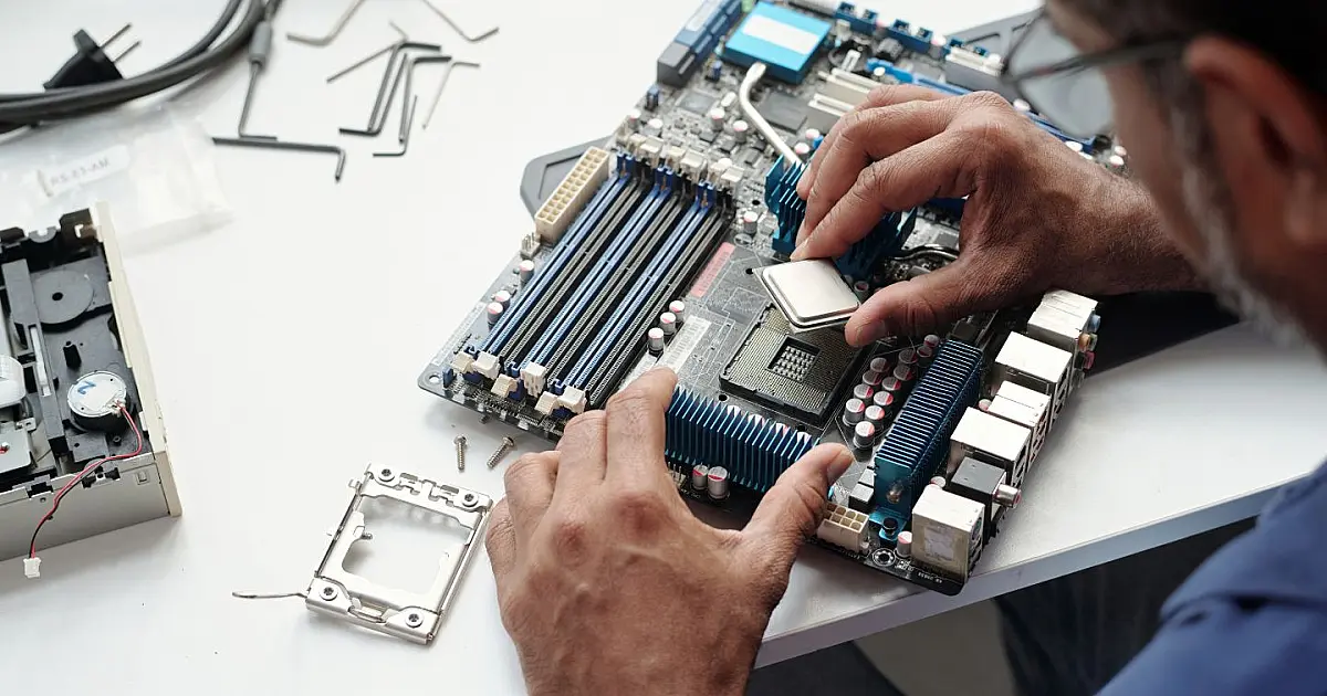 Peças de computador sendo montadas sobre mesa branca, incluindo placa de vídeo e memória RAM.