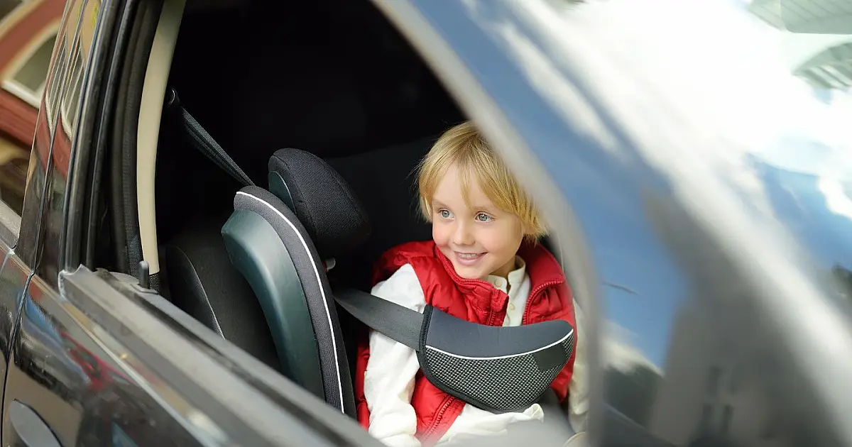 Criança sentada no banco dianteiro de um carro durante trajeto com responsável.