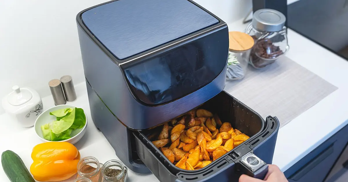 Air fryer moderna posicionada sobre bancada de cozinha.
