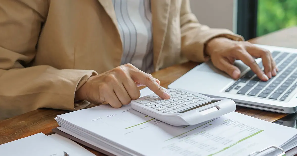 Pessoa calculando despesas domésticas com conta de luz e calculadora