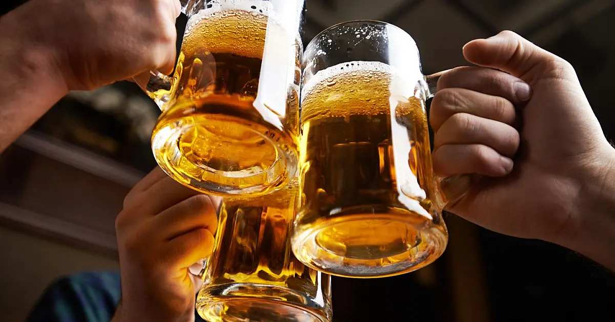 Pessoas brindando com copos de cerveja artesanal em celebração.