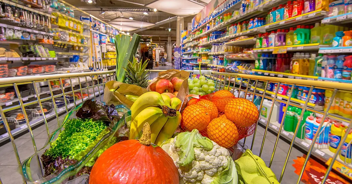 Corredor de supermercado com prateleiras de produtos e carrinhos de compras.