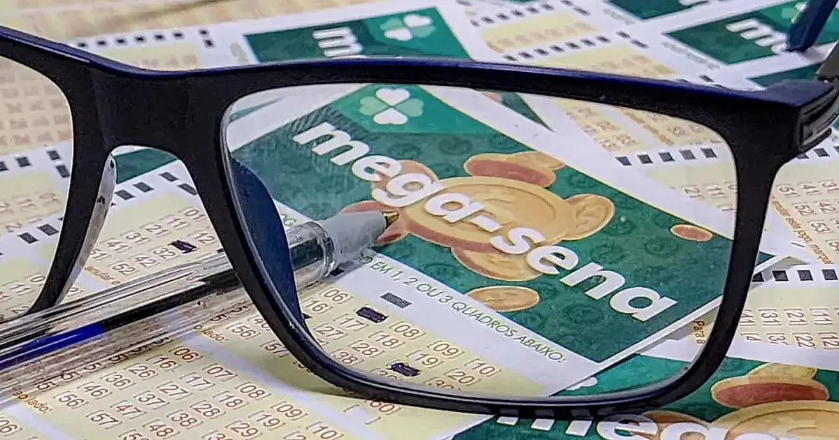 Cartões de aposta da Mega-Sena sobre mesa antes de sorteio.