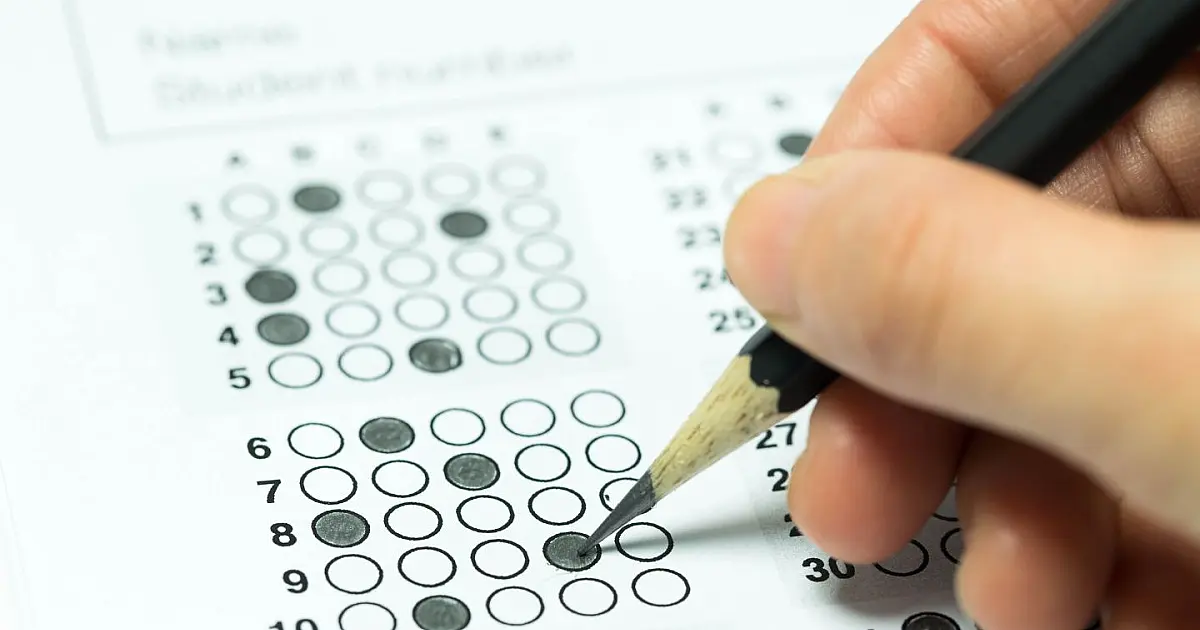 Imagem ilustrativa mostra prova de concurso público com cartão-resposta e caneta sobre a mesa.