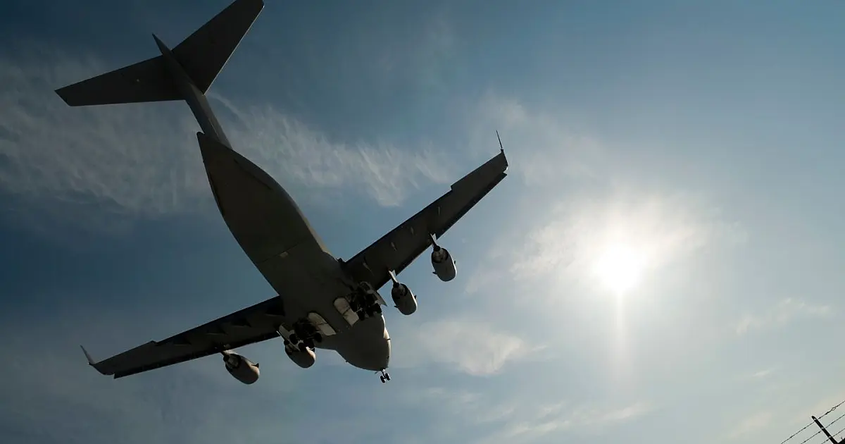 Avião militar sobrevoando região urbana.