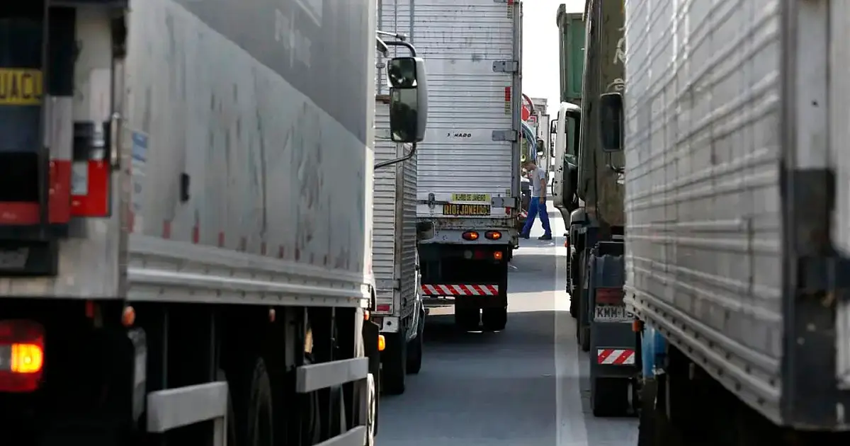 Caminhões trafegando em rodovia brasileira durante o dia.