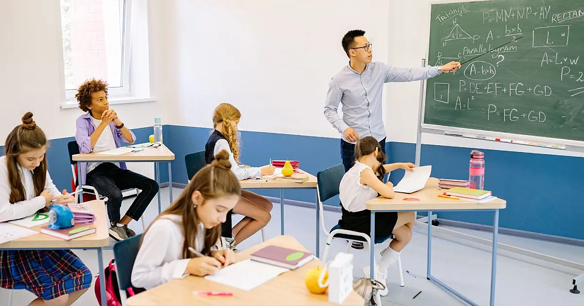 Professor explicando conteúdo de matemática em sala de aula para alunos do ensino básico.