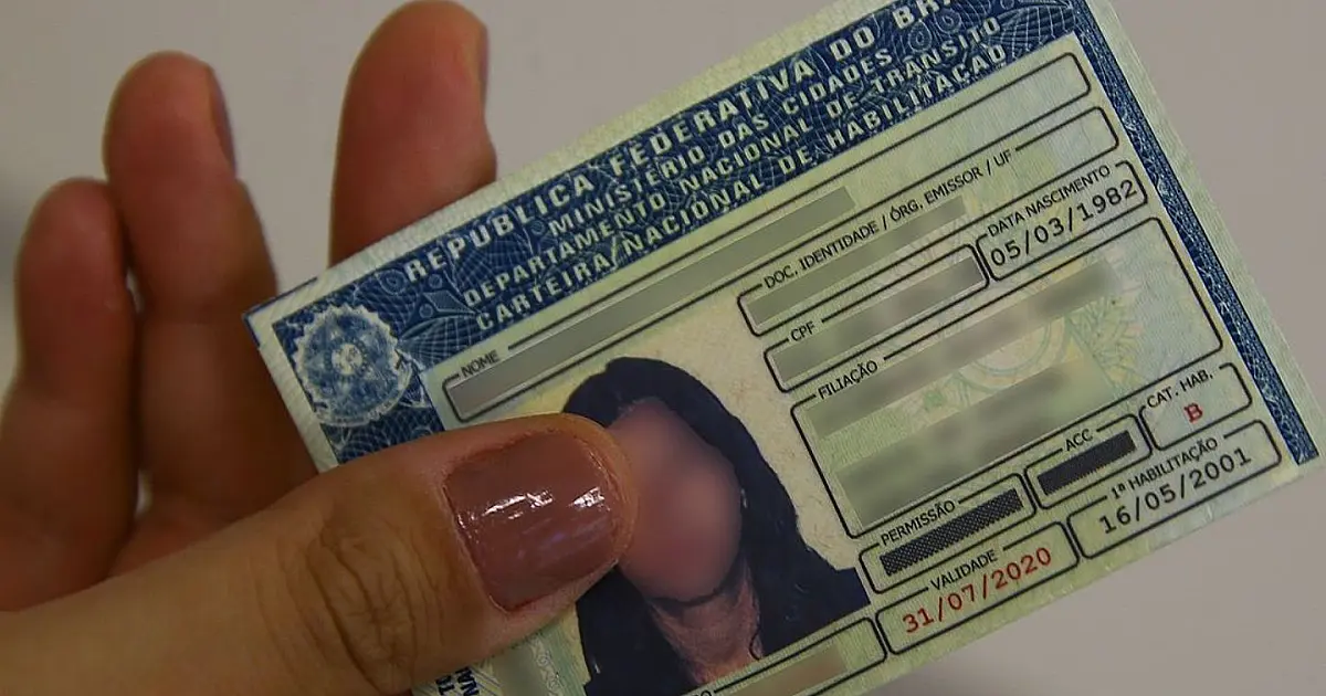 Pessoa segurando carteira nacional de habilitação utilizada em serviços digitais de trânsito.