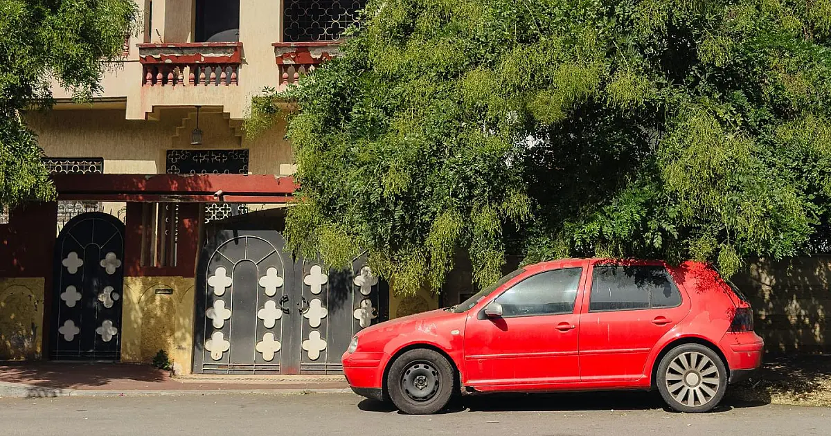 Carro estacionado em frente a garagem de residência em rua residencial.
