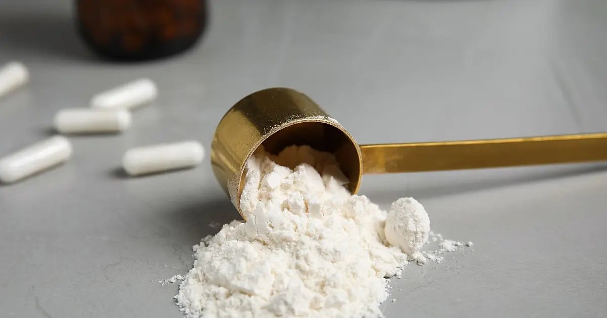 Suplemento de creatina em pó sobre mesa representando nutrição esportiva