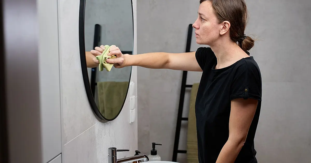 Pessoa sentada no vaso sanitário usando celular no banheiro.