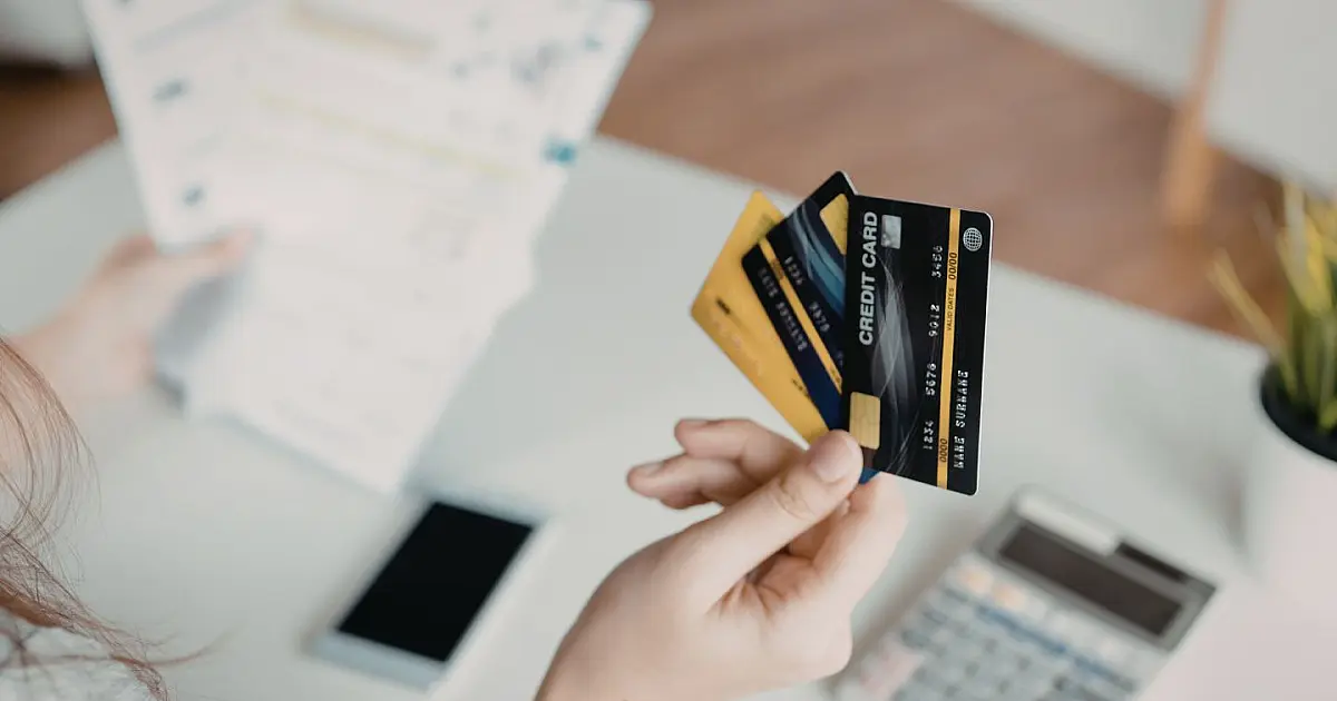 Pessoa segurando cartões de crédito na mão
