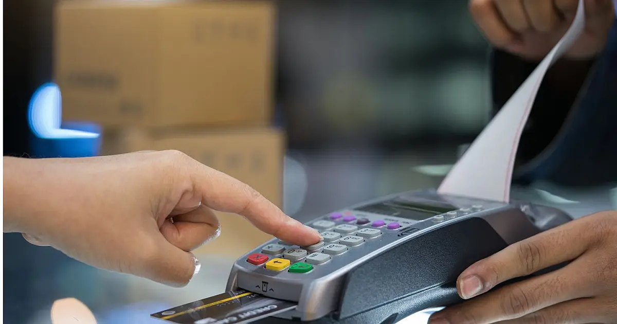 Pessoa realizando pagamento com cartão de crédito em máquina de cartão