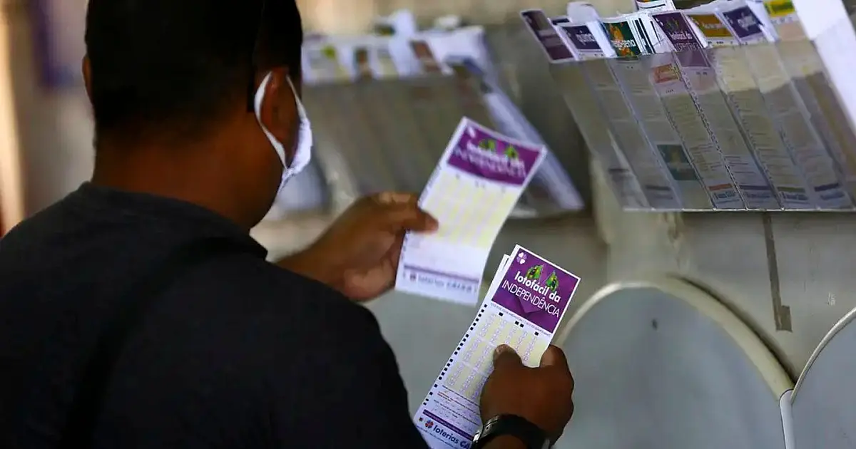 Pessoa preenchendo volante de aposta da Lotofácil