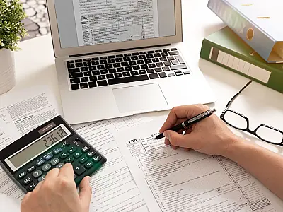 Contribuinte organiza documentos e faz cálculos para preencher a declaração do Imposto de Renda.