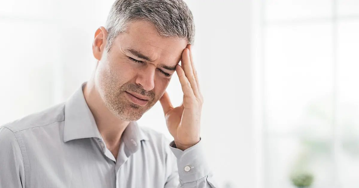 Homem segurando a cabeça devido à dor causada por desidratação