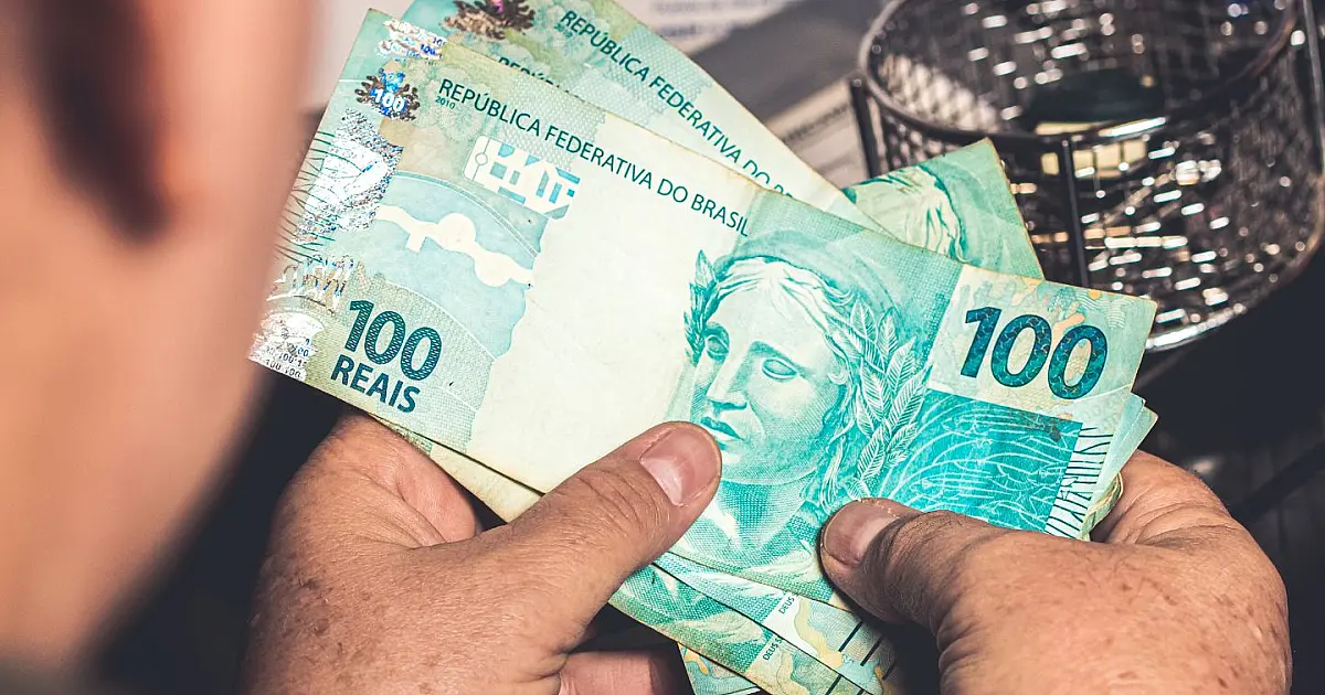 Homem segurando notas de dinheiro representando o salário mínimo no Brasil