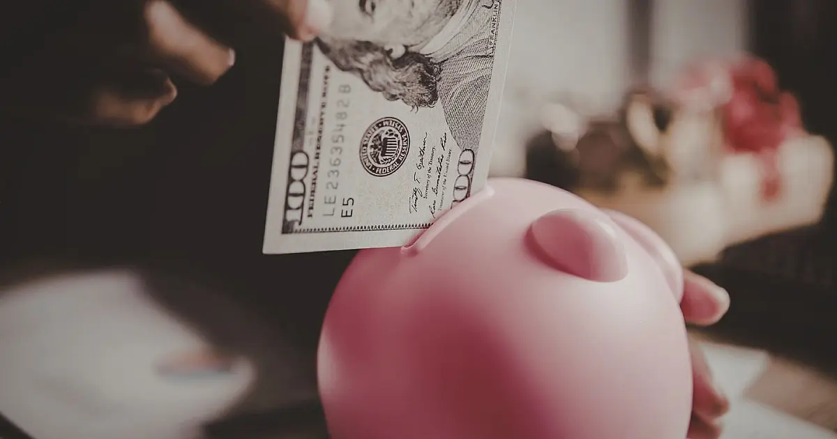 Pessoa colocando dinheiro em um cofre para guardar economias.