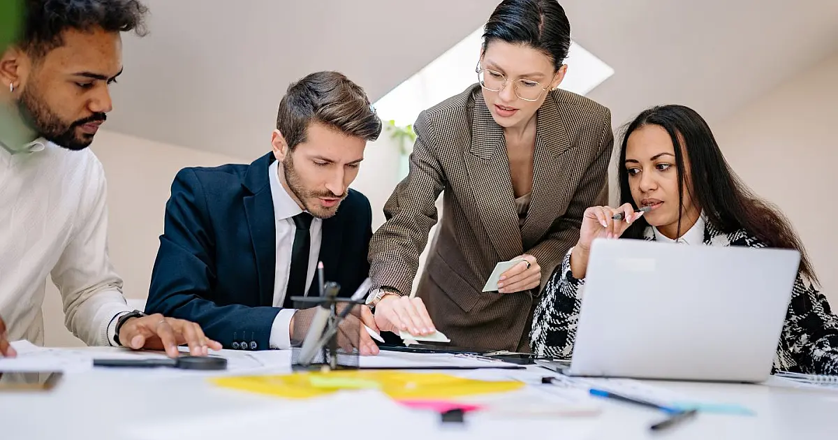Pessoas conversando em reunião enquanto uma delas permanece em silêncio refletindo.