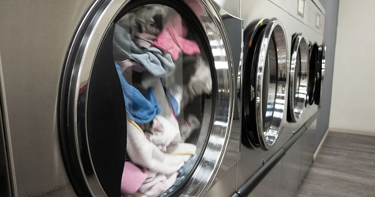 Máquina de lavar roupas aberta com peças de roupa no tambor.