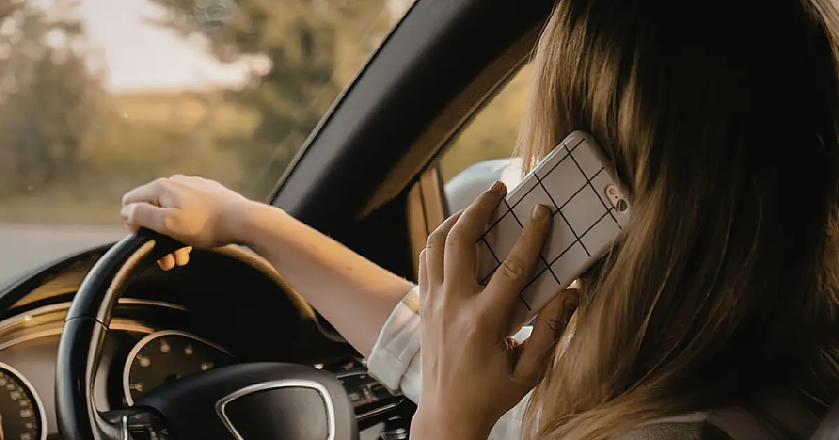 Motorista falando ao celular dentro do carro enquanto dirige