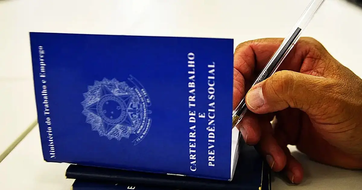 Pessoa assinando carteira de trabalho durante contratação formal