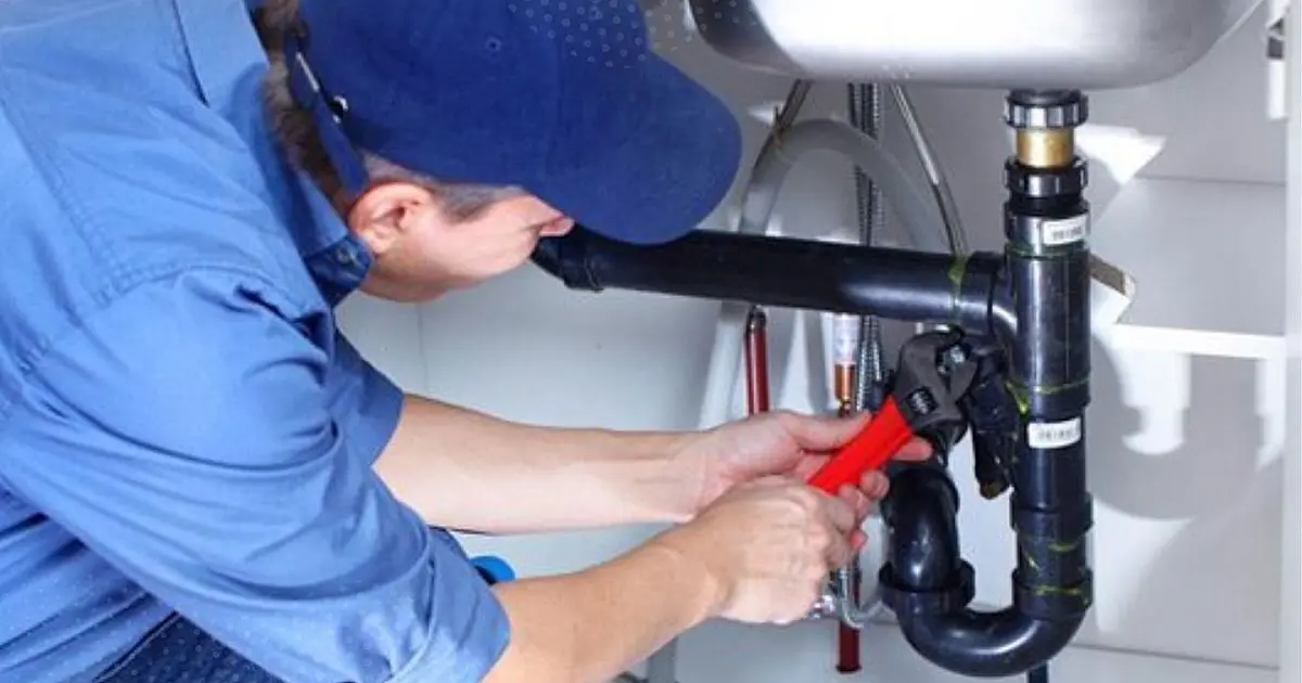 Pessoa utilizando garrafa PET para tentar desentupir pia da cozinha