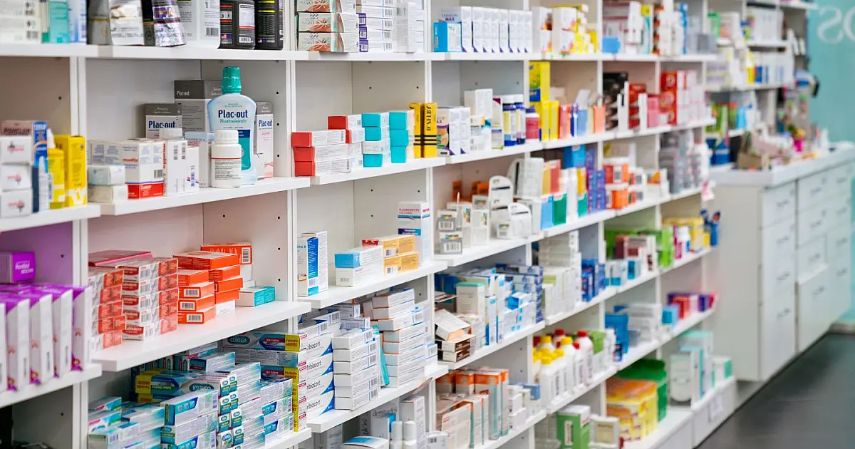 Prateleiras de farmácia com diferentes tipos de medicamentos organizados para venda.