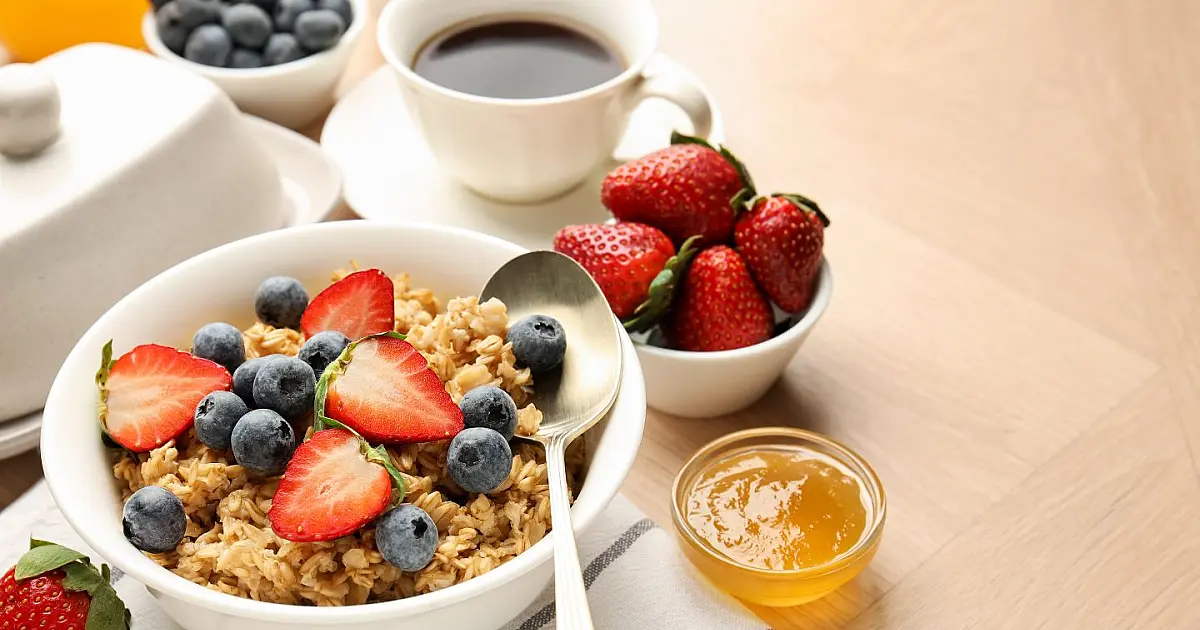 Tigela de aveia com frutas servida em mesa de madeira durante café da manhã saudável