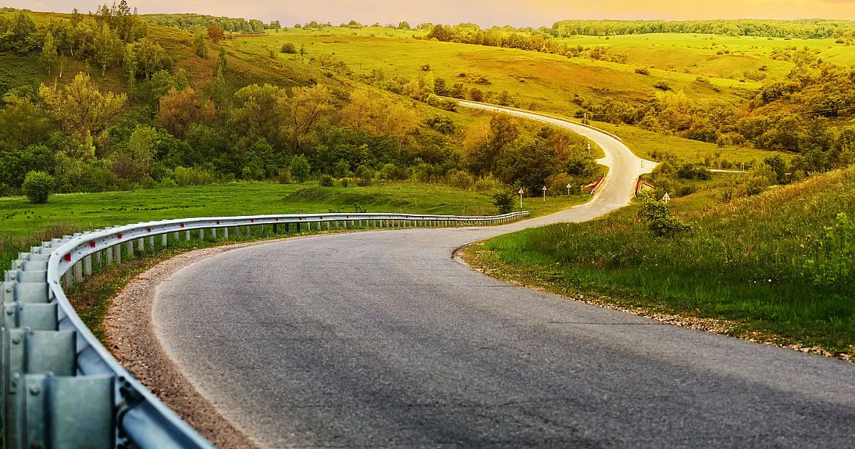 Estrada sinuosa cercada por vegetação representando conectividade em rodovias brasileiras.
