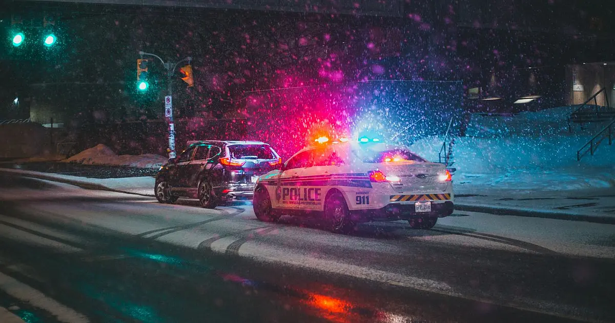 Carro utilitário parado em blitz enquanto policial realiza fiscalização na via.