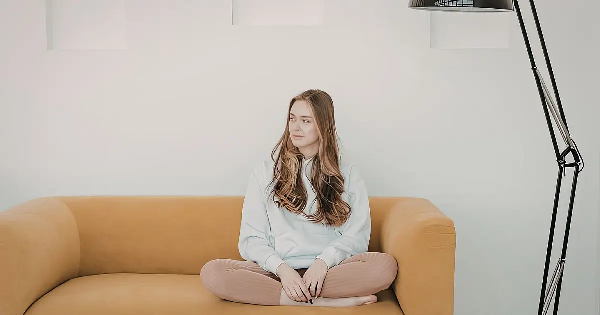 Mulher sentada de pernas cruzadas no sofá em ambiente confortável