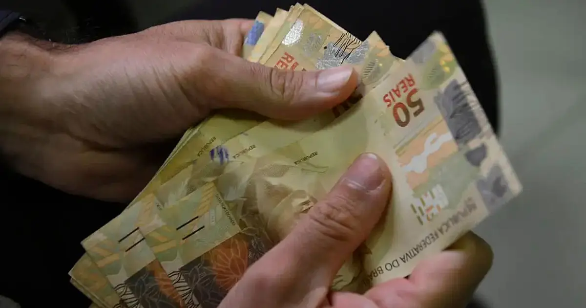 Pessoa contando dinheiro em referência ao reajuste do salário mínimo regional.