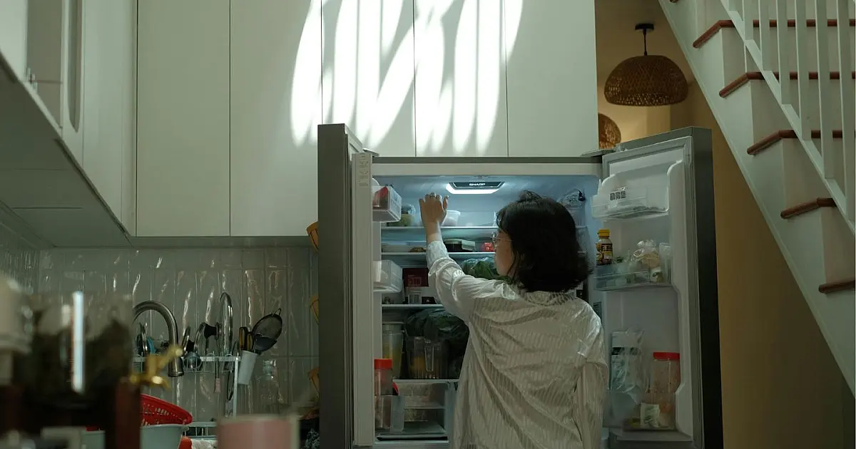 Mulher abrindo geladeira organizada em cozinha