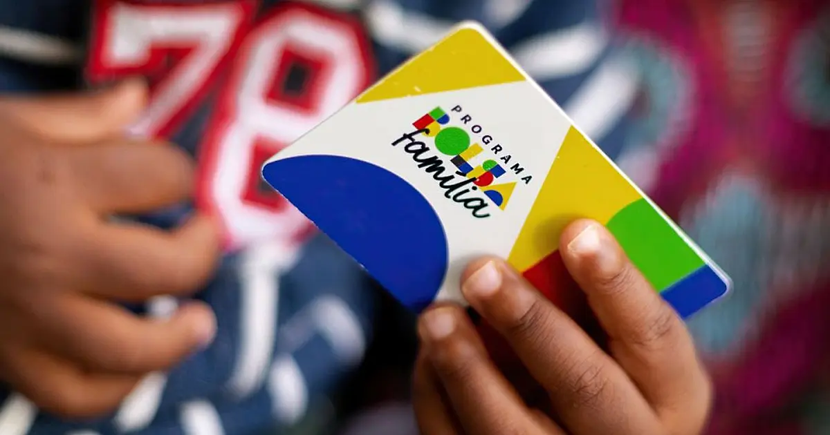 Criança segurando cartão do programa Bolsa Família