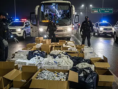Agentes da Polícia Civil analisam carga de medicamentos e anabolizantes apreendida em ônibus vindo do Paraguai.