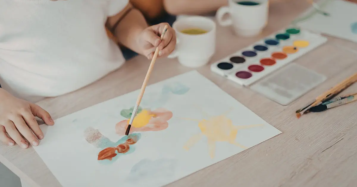 Criança pintando com aquarela durante atividade de desenvolvimento infantil